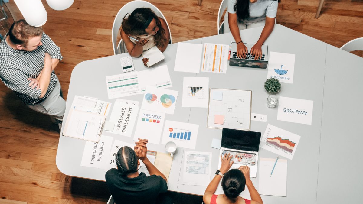 A marketing team working through a strategy on a table of documents.